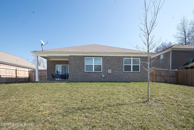 back of house featuring a yard, brick siding, and a fenced backyard
