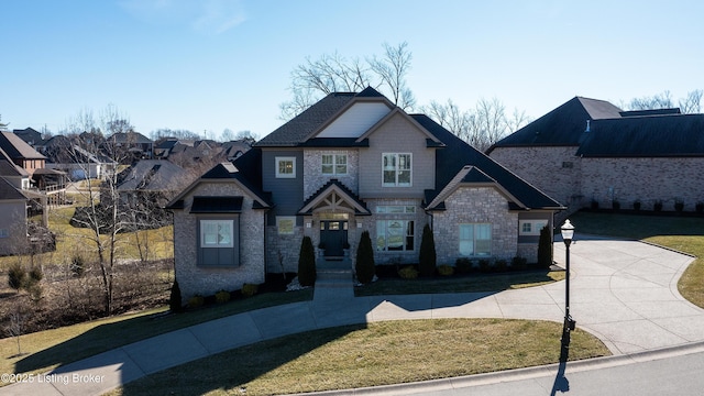 craftsman house with stone siding and a front lawn