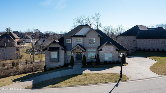 craftsman-style house with stone siding, driveway, and a front yard