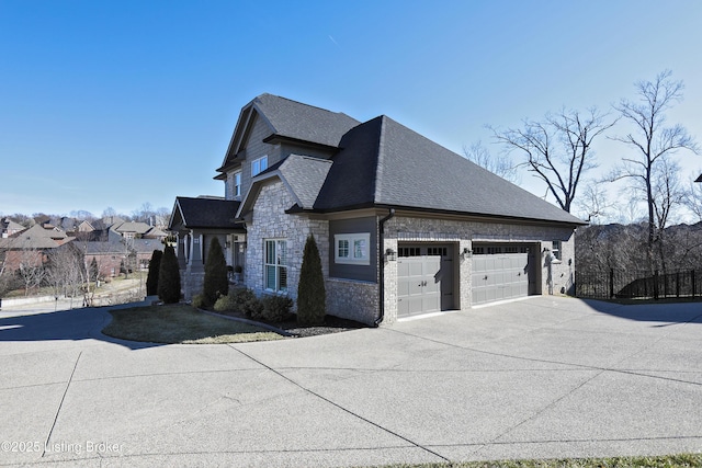 view of home's exterior featuring stone siding, concrete driveway, an attached garage, and a shingled roof