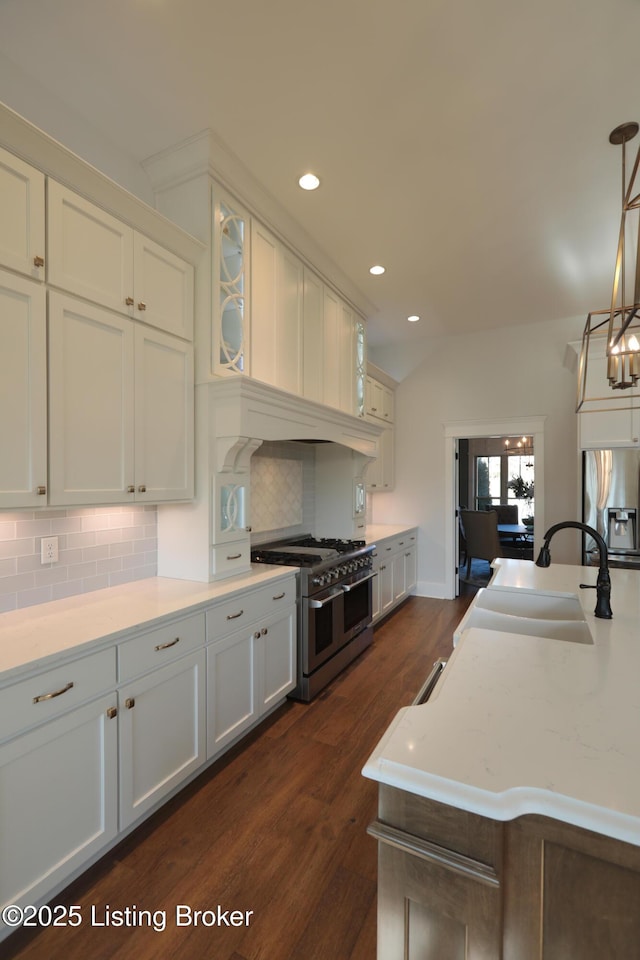 kitchen with dark wood finished floors, backsplash, appliances with stainless steel finishes, and a sink