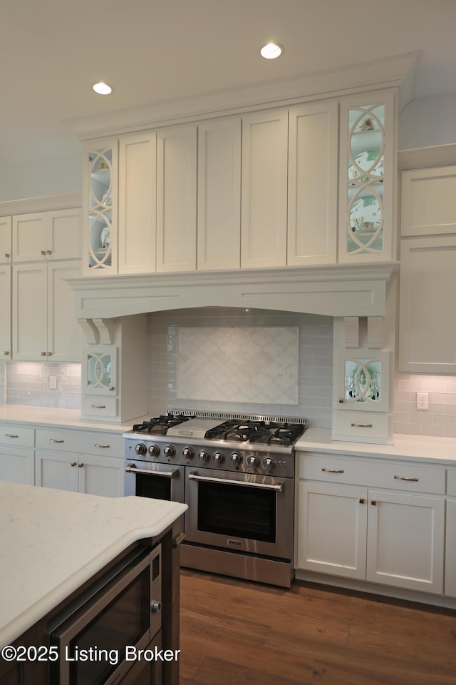 kitchen with tasteful backsplash, glass insert cabinets, dark wood finished floors, appliances with stainless steel finishes, and white cabinets