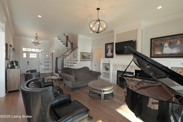 living area with a notable chandelier, crown molding, a fireplace, and stairs