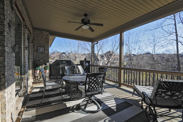 deck featuring area for grilling, outdoor dining area, exterior fireplace, and ceiling fan