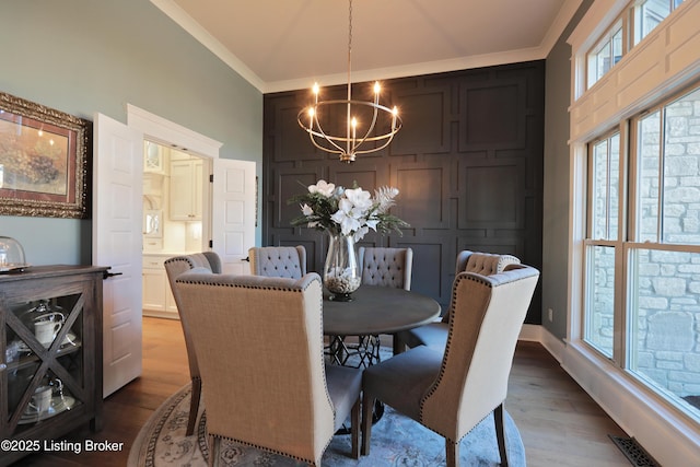 dining space featuring crown molding, a notable chandelier, wood finished floors, and visible vents