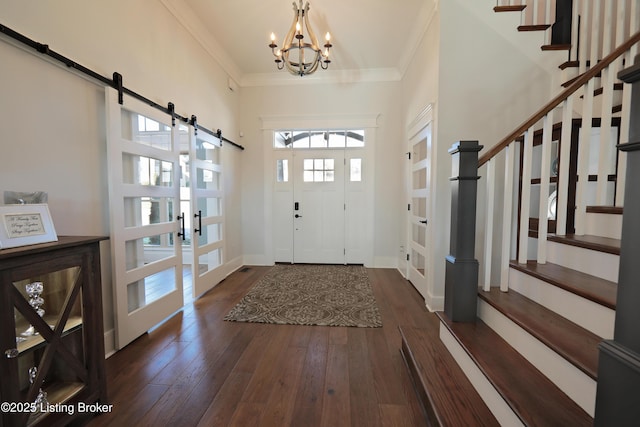 entrance foyer featuring a barn door, wood-type flooring, ornamental molding, and stairs