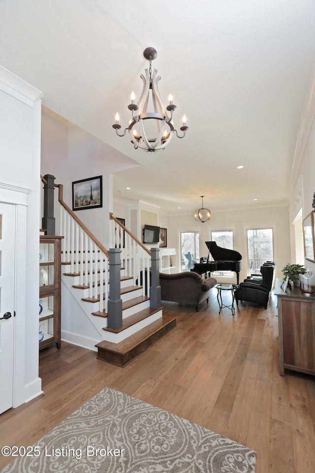 entryway featuring stairs, hardwood / wood-style flooring, a notable chandelier, and crown molding