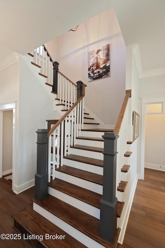 stairs featuring crown molding, baseboards, and wood finished floors