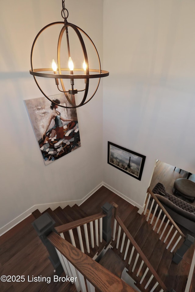 stairway featuring baseboards, an inviting chandelier, and wood finished floors