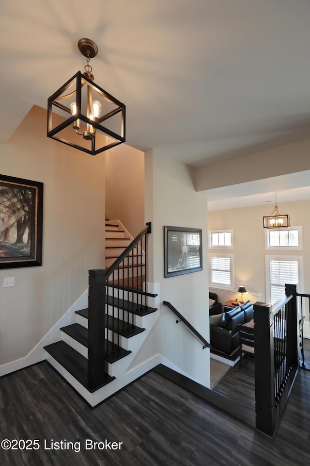 staircase featuring a chandelier, baseboards, and wood finished floors