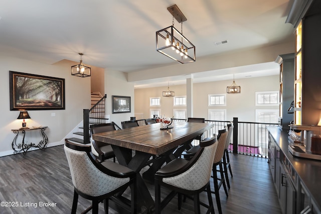 dining area with visible vents, dark wood-type flooring, baseboards, stairway, and a notable chandelier