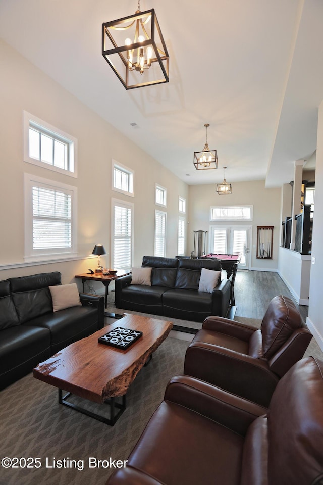 living area featuring a chandelier, baseboards, and wood finished floors