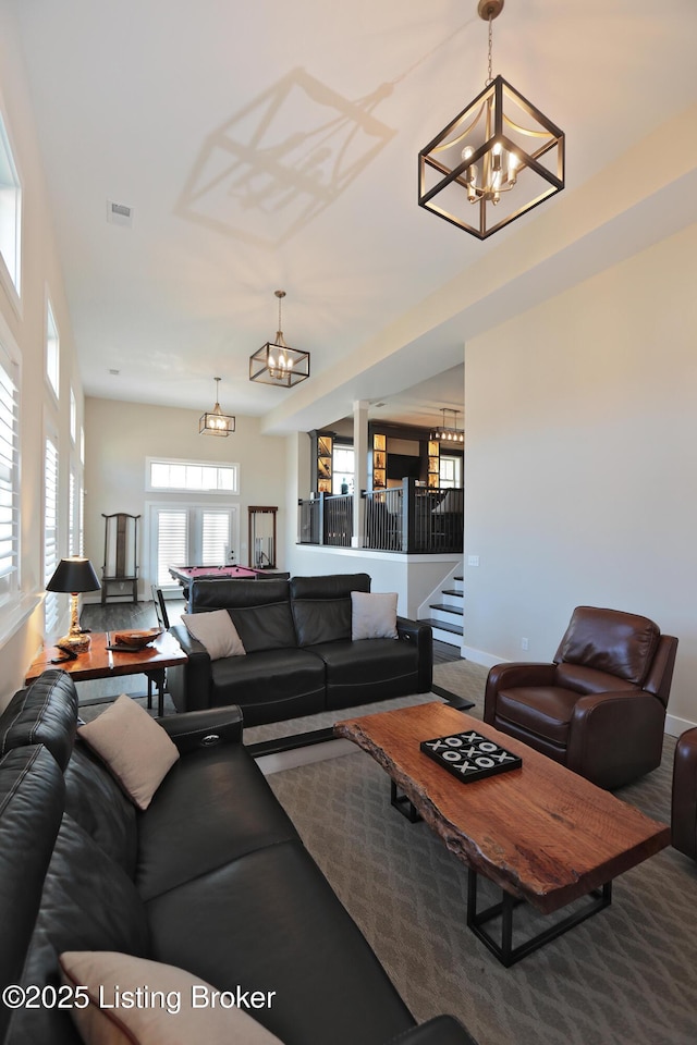 living area featuring a notable chandelier, baseboards, stairs, and visible vents