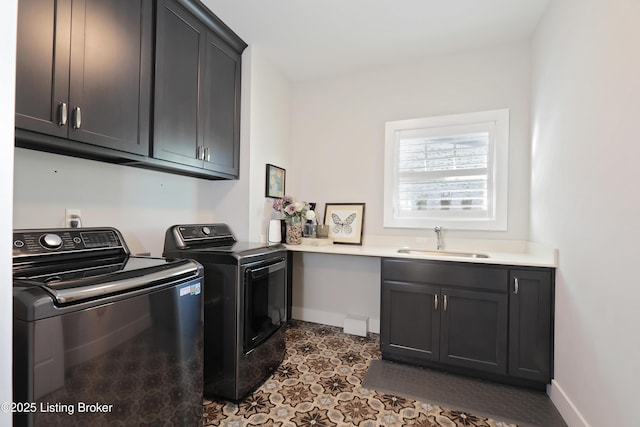 laundry area with a sink, baseboards, cabinet space, and washing machine and dryer