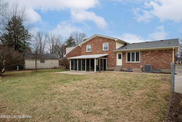 rear view of house featuring brick siding, a lawn, a sunroom, a patio area, and central AC