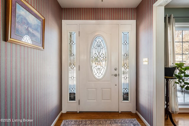 foyer with baseboards, wood finished floors, and wallpapered walls