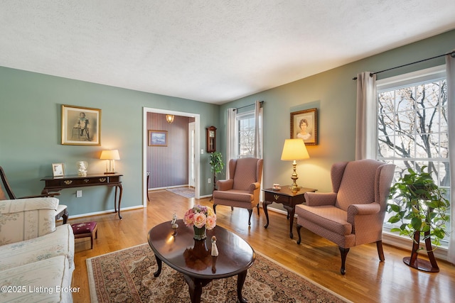 living area with light wood-type flooring, baseboards, and a textured ceiling