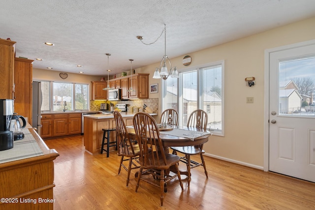 dining area featuring light wood finished floors, baseboards, a textured ceiling, a notable chandelier, and recessed lighting