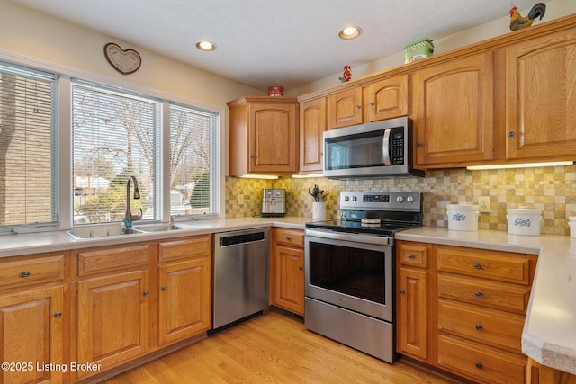 kitchen featuring light wood-style floors, stainless steel appliances, a sink, and light countertops