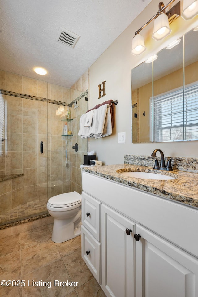 full bath with visible vents, toilet, a stall shower, a textured ceiling, and vanity