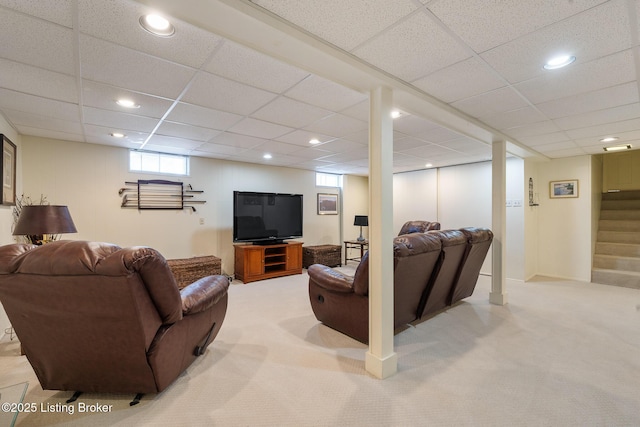 living room with a paneled ceiling, stairway, and light colored carpet