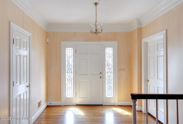 entrance foyer with baseboards, visible vents, ornamental molding, light wood-style floors, and a notable chandelier