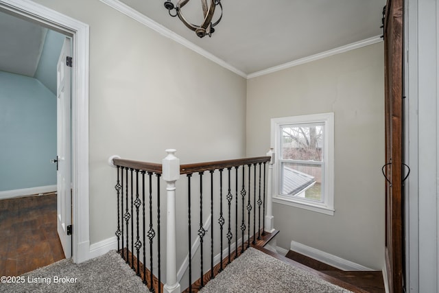 hall with an upstairs landing, wood finished floors, baseboards, and ornamental molding