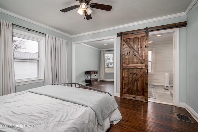 bedroom with visible vents, a barn door, wood-type flooring, crown molding, and baseboards