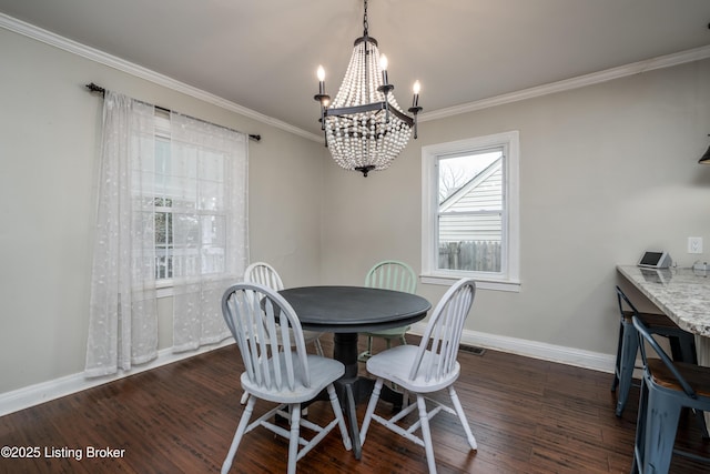 dining room with an inviting chandelier, crown molding, baseboards, and wood finished floors