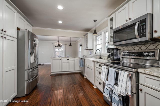 kitchen featuring ornamental molding, decorative backsplash, appliances with stainless steel finishes, a peninsula, and a sink