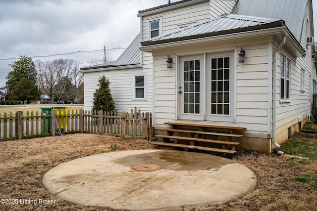 rear view of house featuring a patio area, entry steps, metal roof, and fence