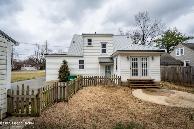 rear view of house featuring a patio area, entry steps, metal roof, and a fenced backyard