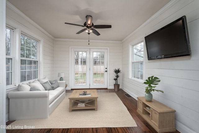 living room with dark wood finished floors, visible vents, a ceiling fan, and ornamental molding