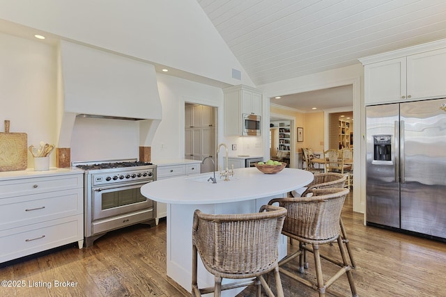 kitchen with hardwood / wood-style floors, stainless steel appliances, white cabinets, light countertops, and lofted ceiling