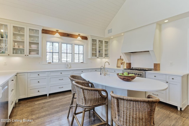 kitchen featuring a kitchen bar, dark wood finished floors, range with gas cooktop, custom exhaust hood, and vaulted ceiling