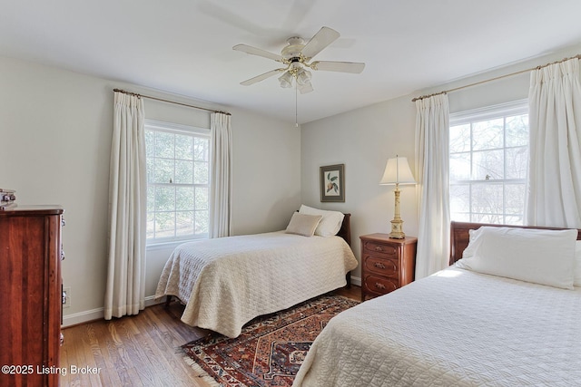 bedroom with ceiling fan, baseboards, multiple windows, and wood finished floors