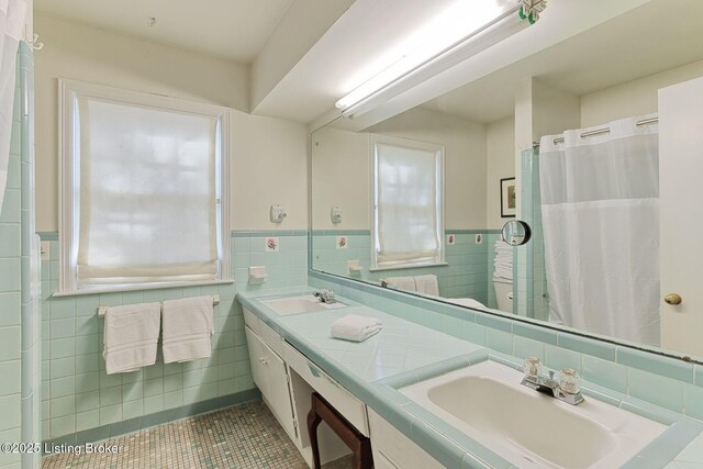 full bathroom with tile patterned floors, tile walls, and a sink