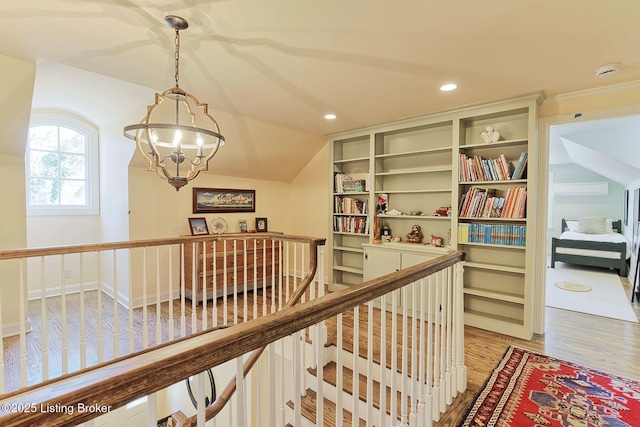 hallway featuring an inviting chandelier, lofted ceiling, recessed lighting, light wood-style floors, and an upstairs landing