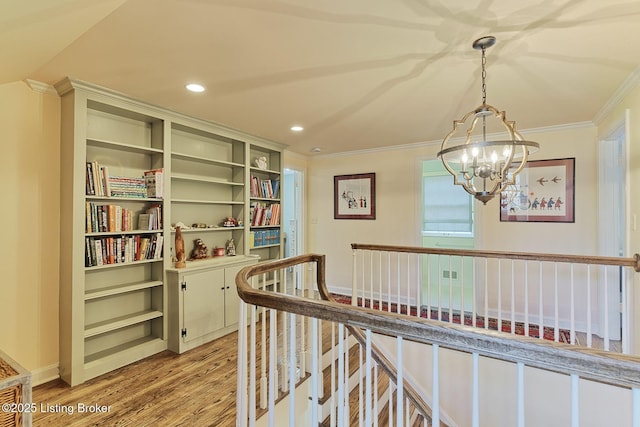 hall with an upstairs landing, light wood-style flooring, ornamental molding, recessed lighting, and an inviting chandelier