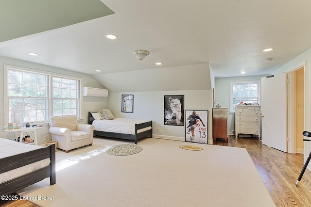 bedroom with a wall unit AC, recessed lighting, wood finished floors, and vaulted ceiling