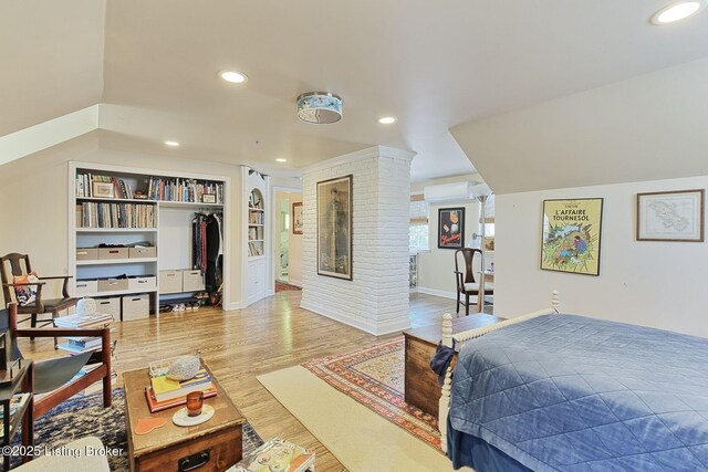 bedroom featuring recessed lighting, a closet, wood finished floors, and a wall unit AC