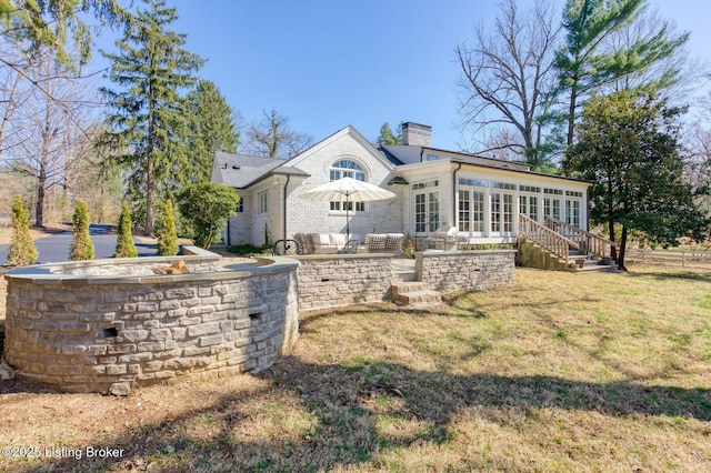 exterior space with a yard, a sunroom, a chimney, a patio area, and brick siding