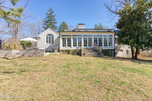 back of property featuring entry steps, a yard, and a chimney