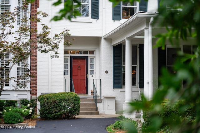 entrance to property featuring brick siding and stucco siding