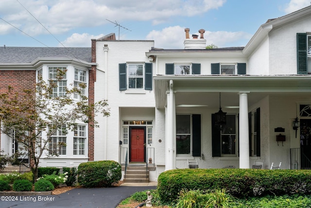 townhome / multi-family property with a chimney and brick siding