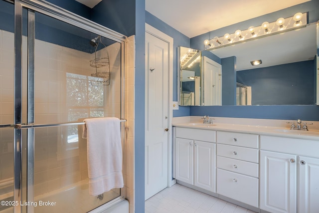 full bath featuring double vanity, a stall shower, tile patterned flooring, and a sink