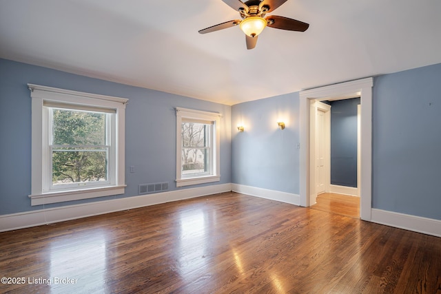 spare room featuring visible vents, ceiling fan, baseboards, and wood finished floors