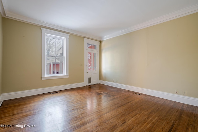 empty room featuring ornamental molding, wood finished floors, and visible vents