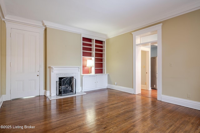 unfurnished living room with ornamental molding, a fireplace with raised hearth, baseboards, and wood finished floors