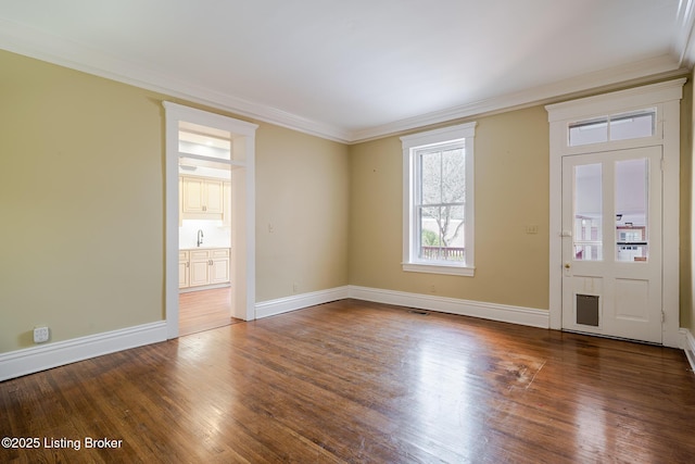 entrance foyer with ornamental molding, wood finished floors, and baseboards